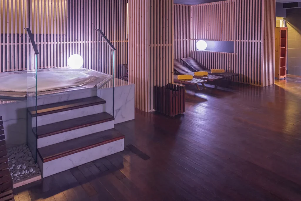 Spa moderno con jacuzzi y camastros de madera.