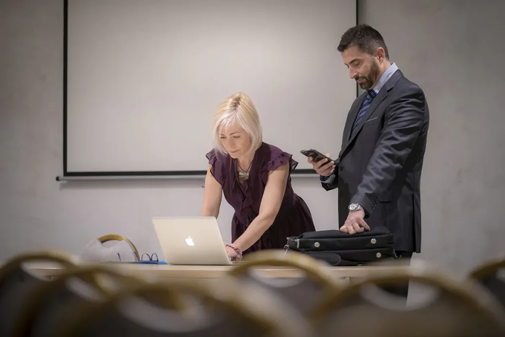 Dos personas trabajando juntas en una presentaci&oacute;n en una sala de conferencias.