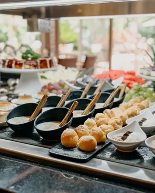 Buffet con postres y frutas variadas en platos y tazones.