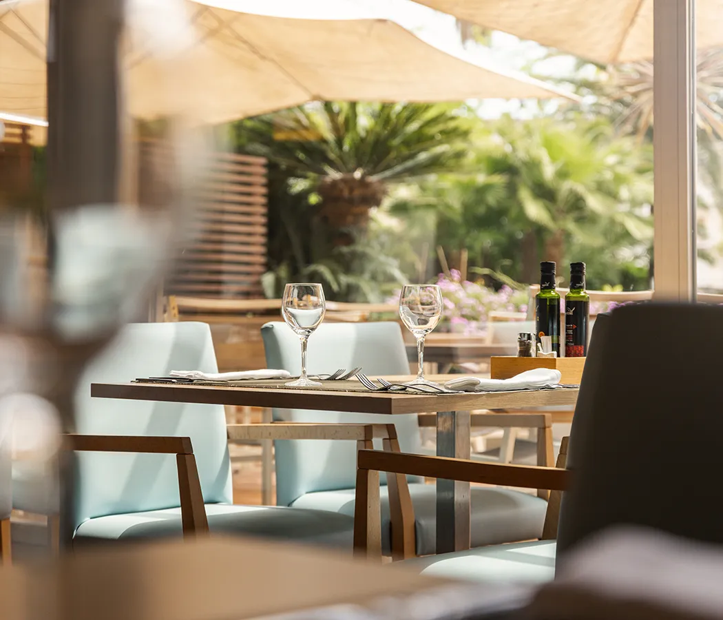 Mesa de restaurante al aire libre con copas y botellas de aceite.