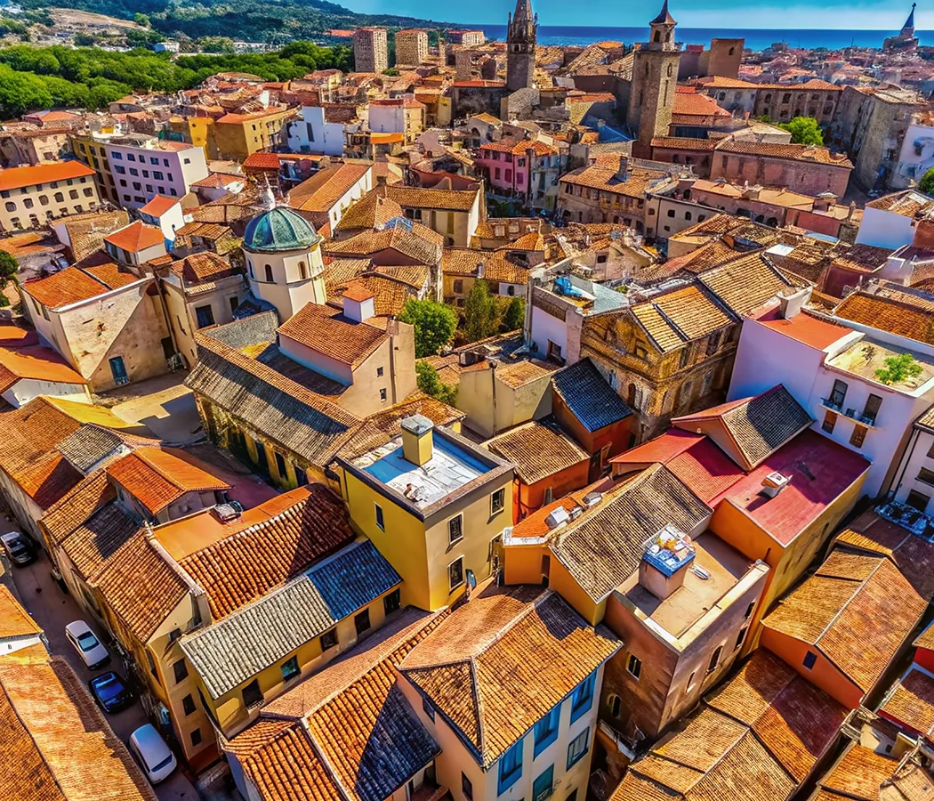 Vista a&eacute;rea de un colorido pueblo mediterr&aacute;neo con techos de tejas rojas.
