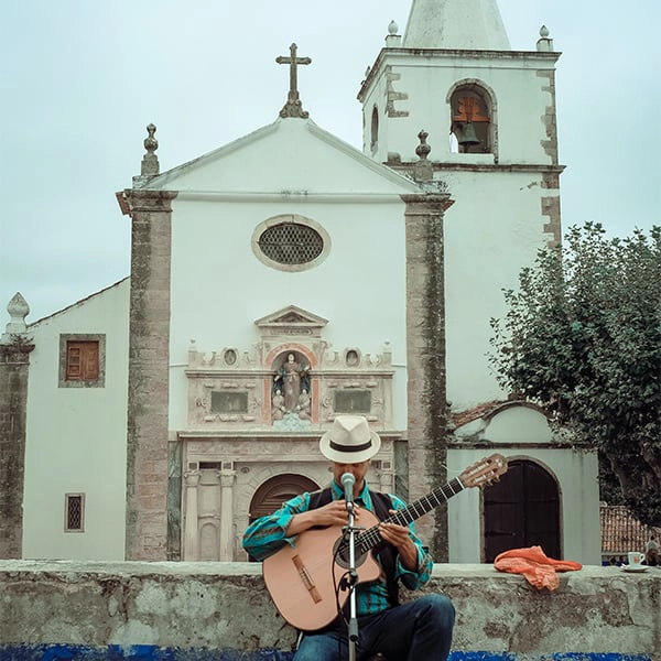 M&uacute;sico toca viol&atilde;o em frente a uma igreja hist&oacute;rica.