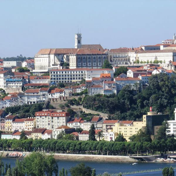 Vista panor&acirc;mica de cidade com rio e pr&eacute;dios hist&oacute;ricos ao fundo.