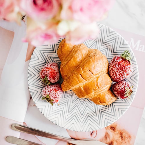 Croissant com morangos em um prato decorado sobre a mesa.