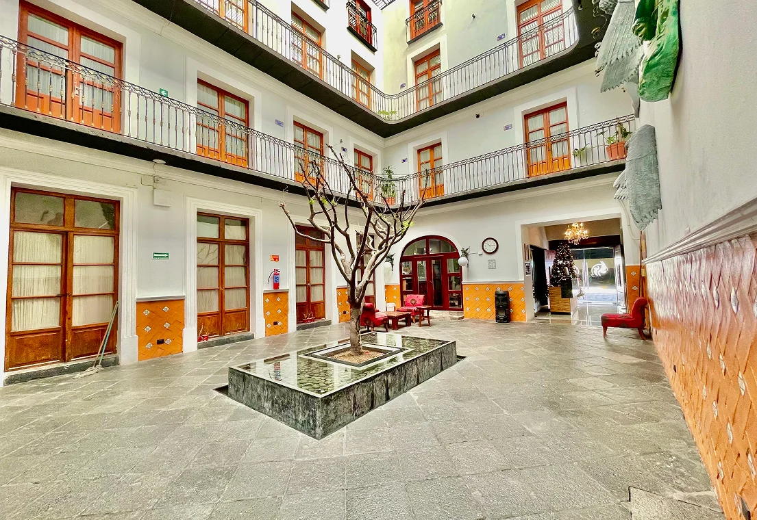 Patio interior con &aacute;rbol central y balcones alrededor.