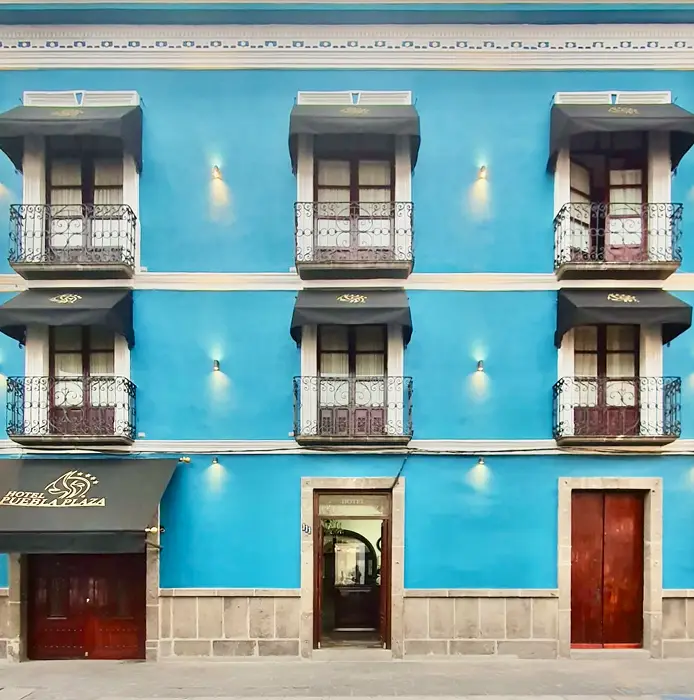 Edificio azul con seis balcones y puerta de entrada en el centro.