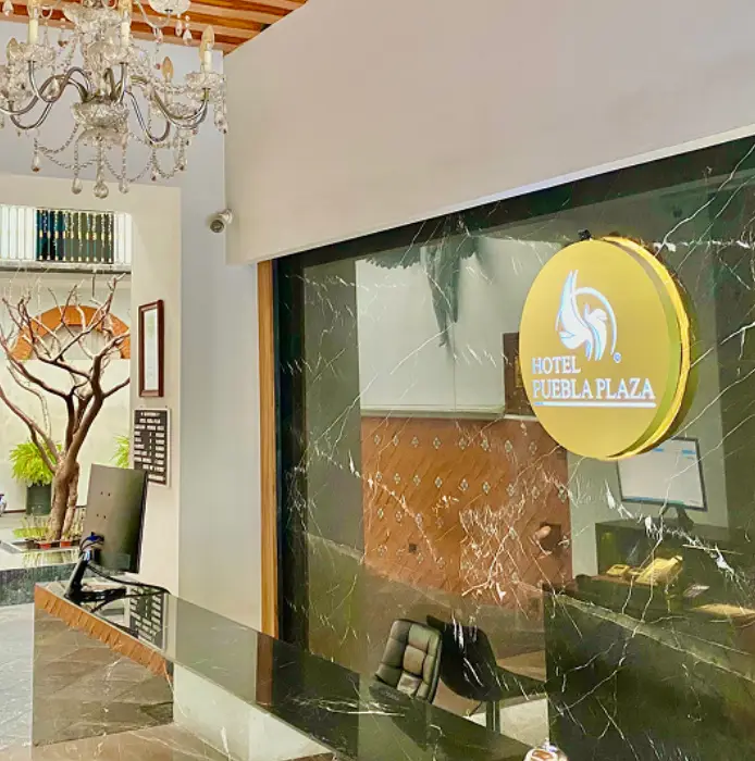 Recepci&oacute;n del Hotel Puebla Plaza con decoraci&oacute;n elegante y candelabro.