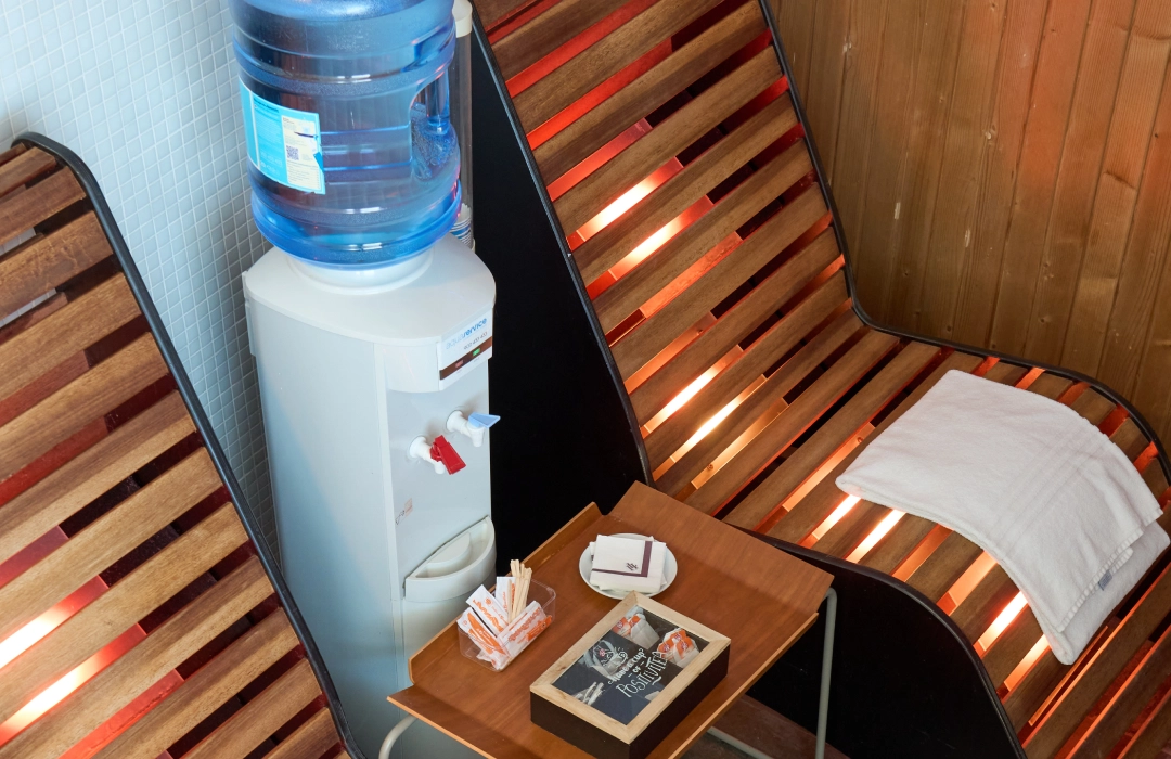 Enfriador de agua junto a sillas de madera y mesa con charola.