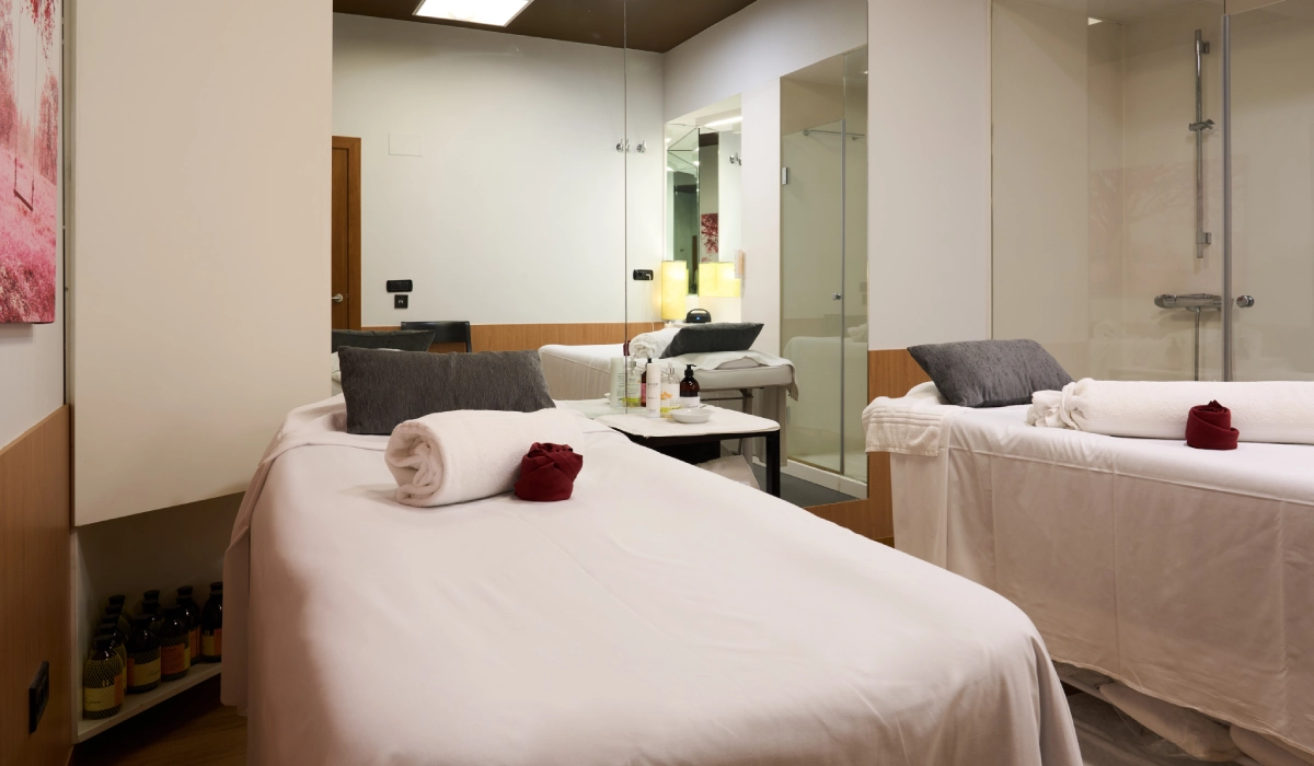 Sala de spa con dos camas de masaje, ambiente acogedor y elegante.