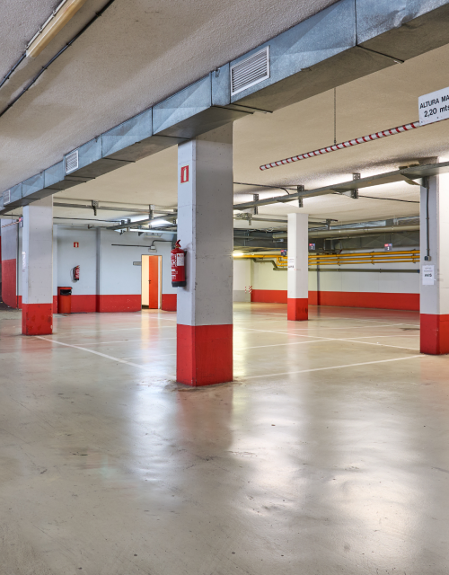Estacionamiento subterr&aacute;neo vac&iacute;o con columnas pintadas de rojo.
