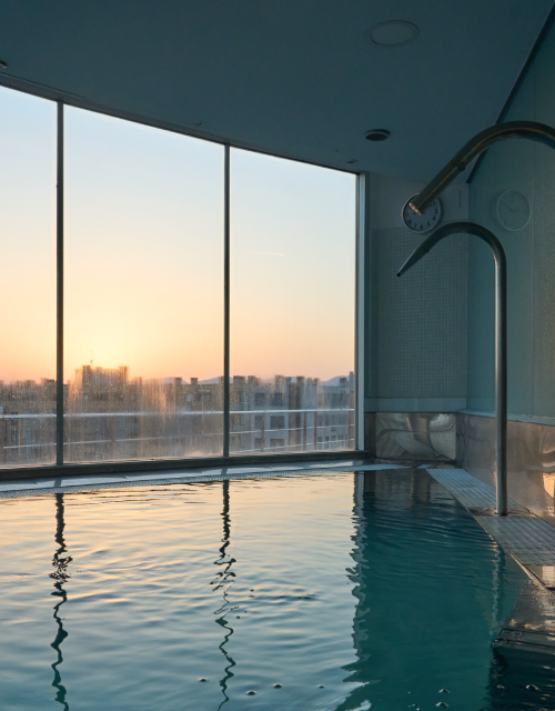 Piscina interior con ventana y vista al amanecer.