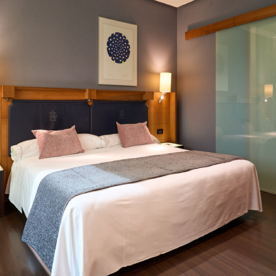 Cama doble en habitaci&oacute;n moderna con luz suave y decoraci&oacute;n minimalista.