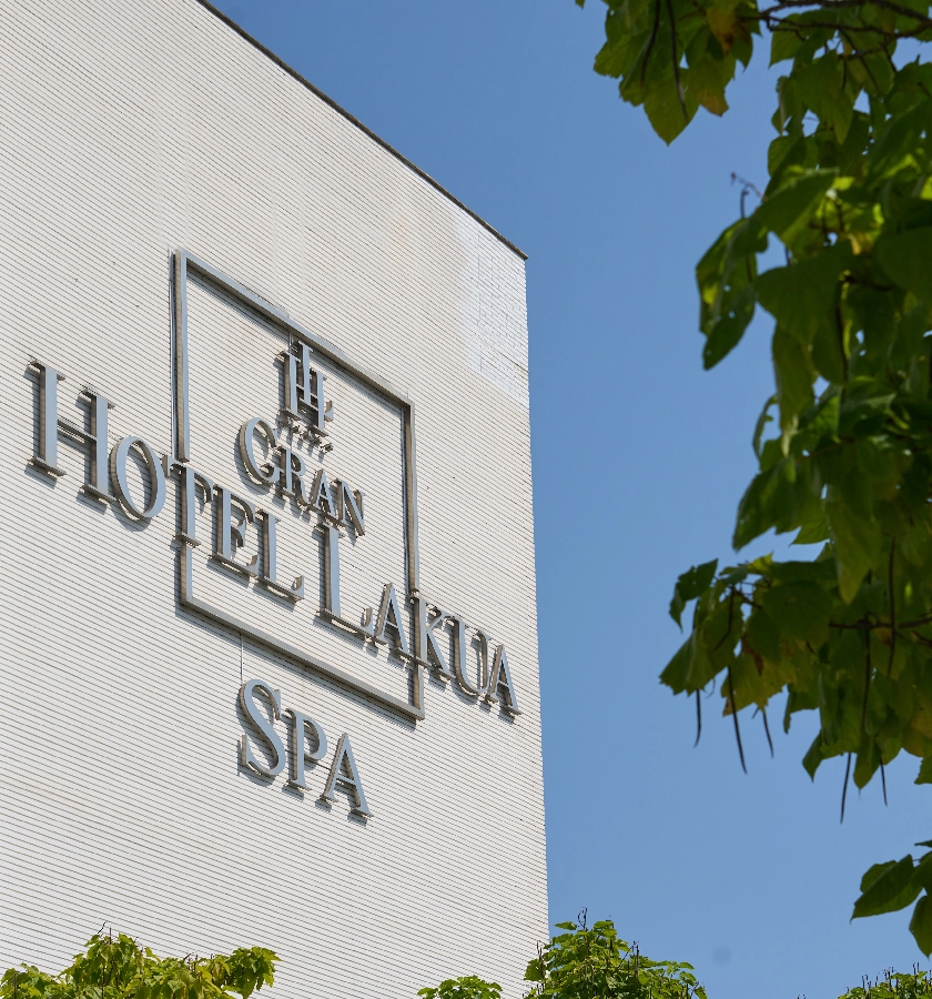 Edificio del Gran Hotel Lakua SPA con cielo y hojas verdes.