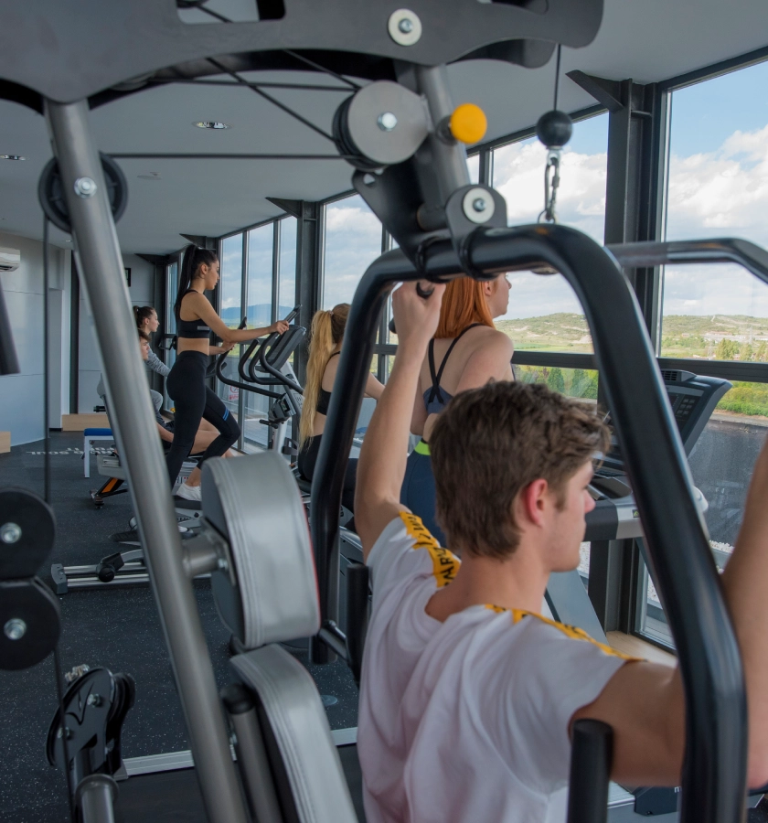 Personas ejercit&aacute;ndose en una sala de gimnasio con ventanales.