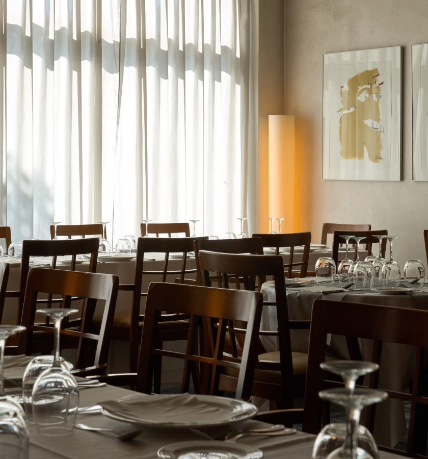 Restaurante con mesas preparadas y luz suave entrando por la ventana.