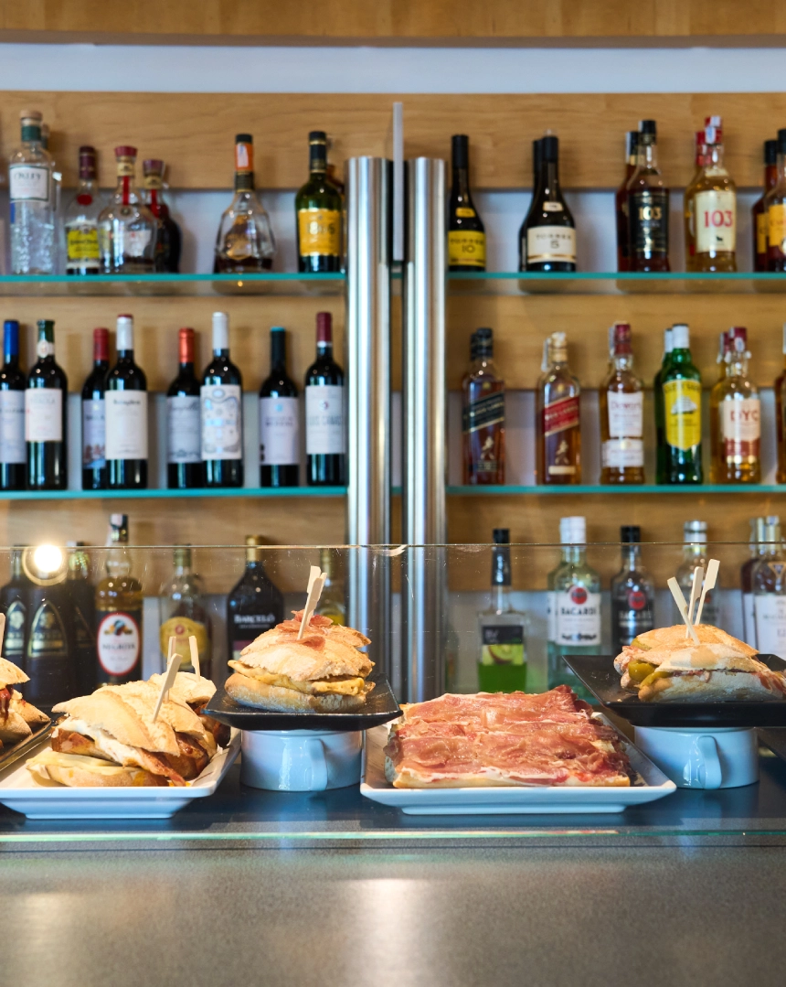 Bocadillos y botellas en estanter&iacute;a de un bar.