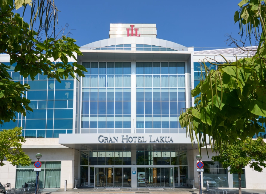 Fachada del Gran Hotel Lakua con ventanas y &aacute;rboles al frente.