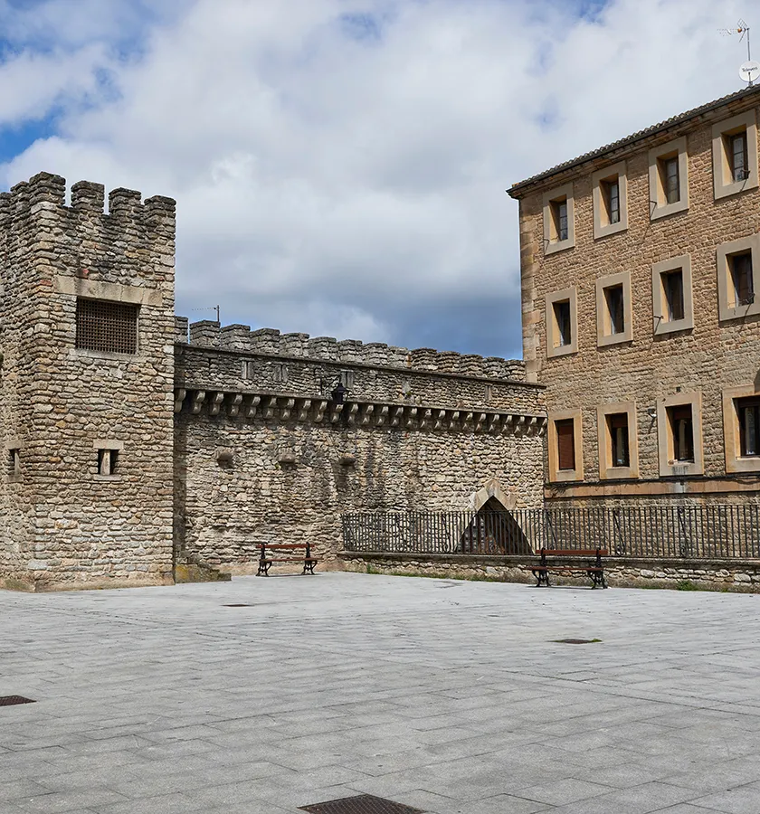 Edificio antiguo de piedra y torre&oacute;n bajo un cielo parcialmente nublado.
