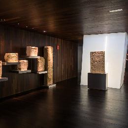 Exhibici&oacute;n de esculturas talladas en un museo con iluminaci&oacute;n c&aacute;lida.