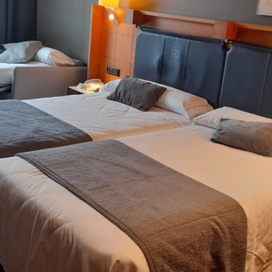 Habitaci&oacute;n de hotel con dos camas dobles y iluminaci&oacute;n c&aacute;lida.