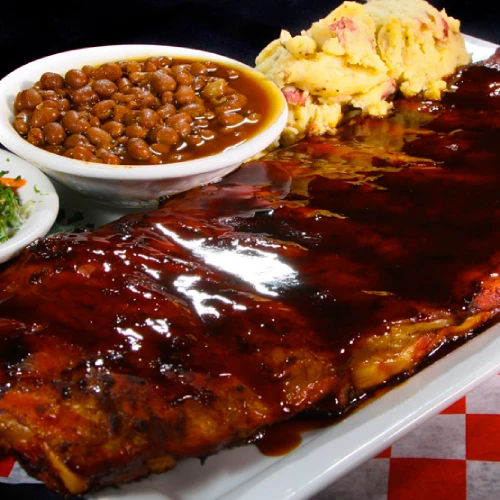 Costillas con salsa BBQ, acompañadas de frijoles, puré de papa y ensalada.