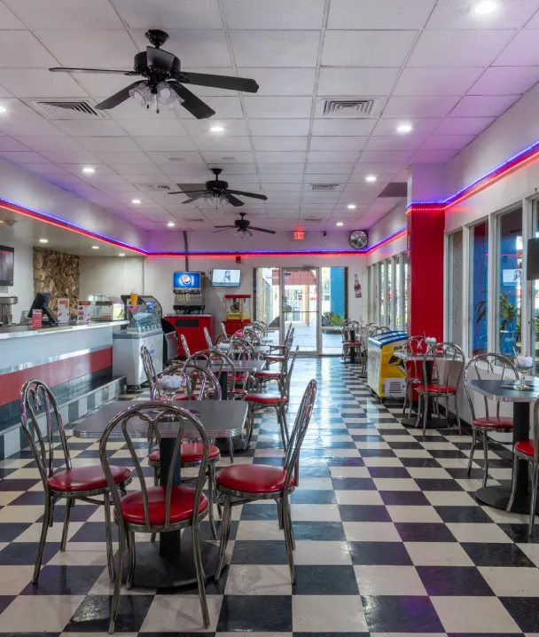 Restaurante vintage con piso de cuadros y sillas rojas, estilo de los a&ntilde;os 50.