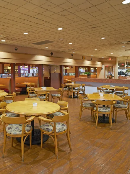 Restaurante con mesas y sillas de madera, decoraci&oacute;n c&aacute;lida e iluminaci&oacute;n tenue.