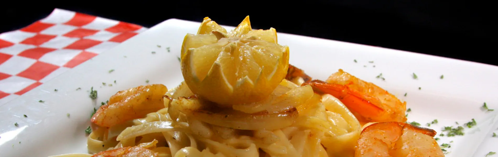 Plato de pasta con camarones y medio limón adornando.
