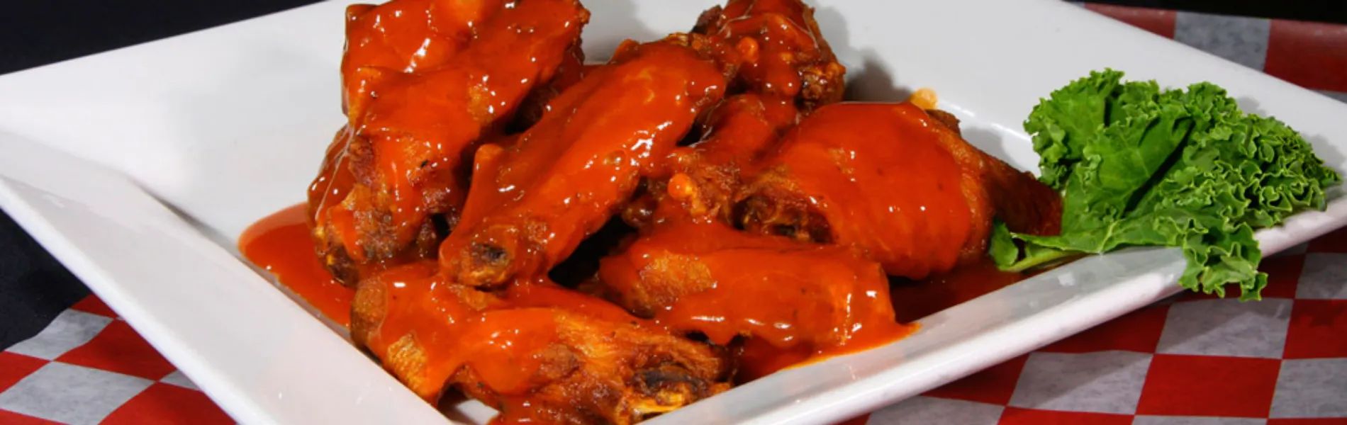 Alitas de pollo en salsa picante servidas en un plato con guarnición de lechuga.