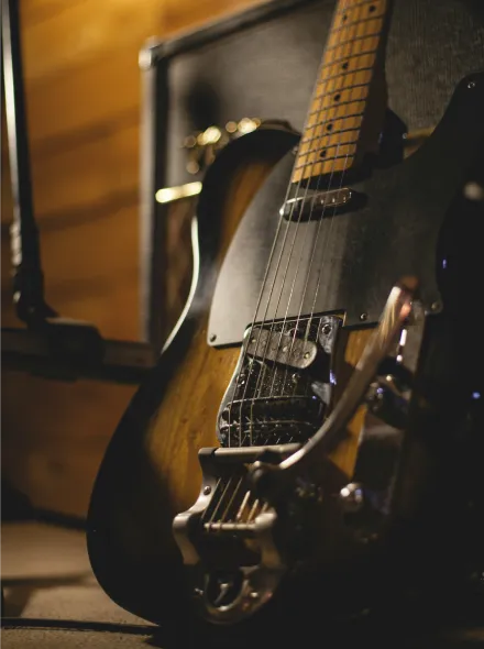 Guitarra el&eacute;ctrica apoyada en un amplificador en una sala de madera.