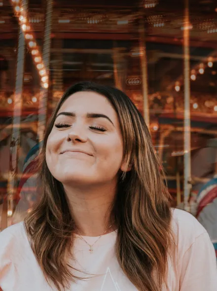 No puedo identificar a las personas en la imagen, pero parece una mujer sonriente en un carrusel.