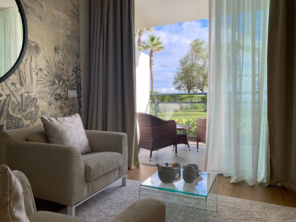 Cozy living room with armchair, glass table, and balcony view.