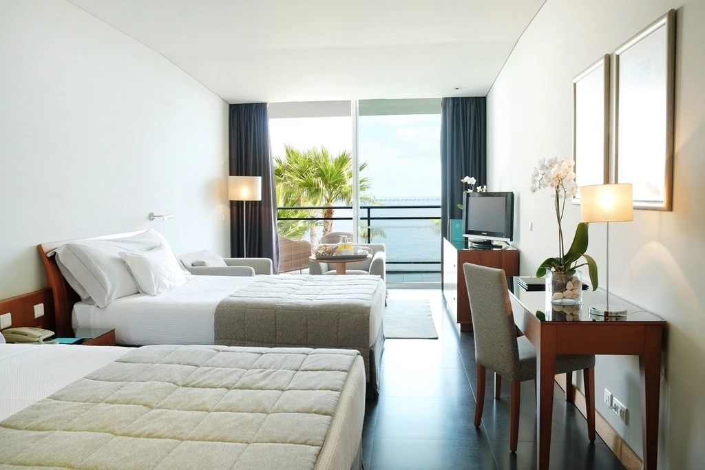 Hotel room with twin beds and a balcony view of the sea.
