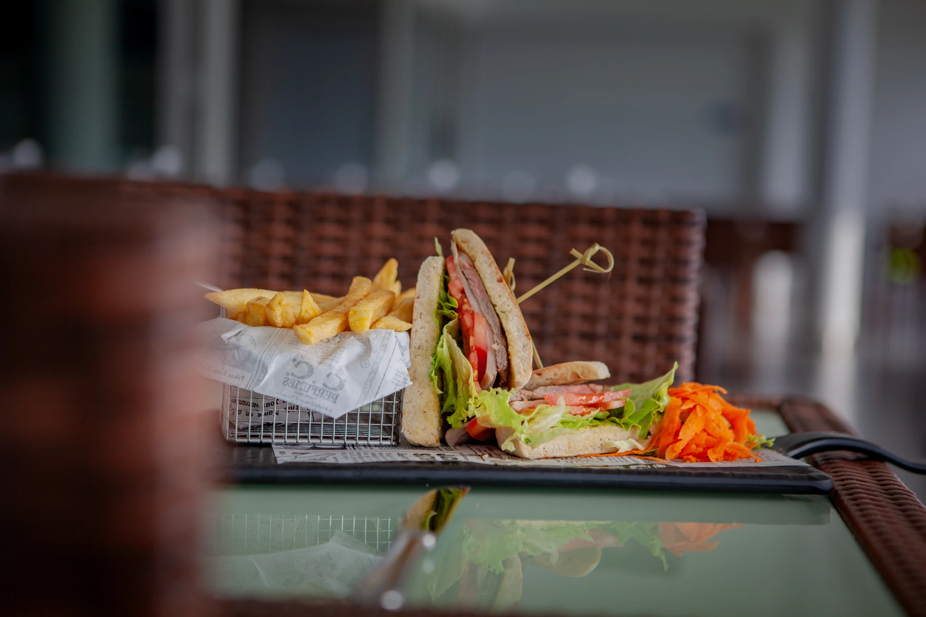 Sandwich with fries and grated carrots on a table.