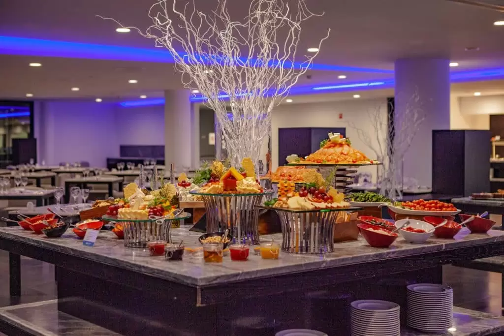 Buffet table with assorted food and elegant decor in a lit dining area.