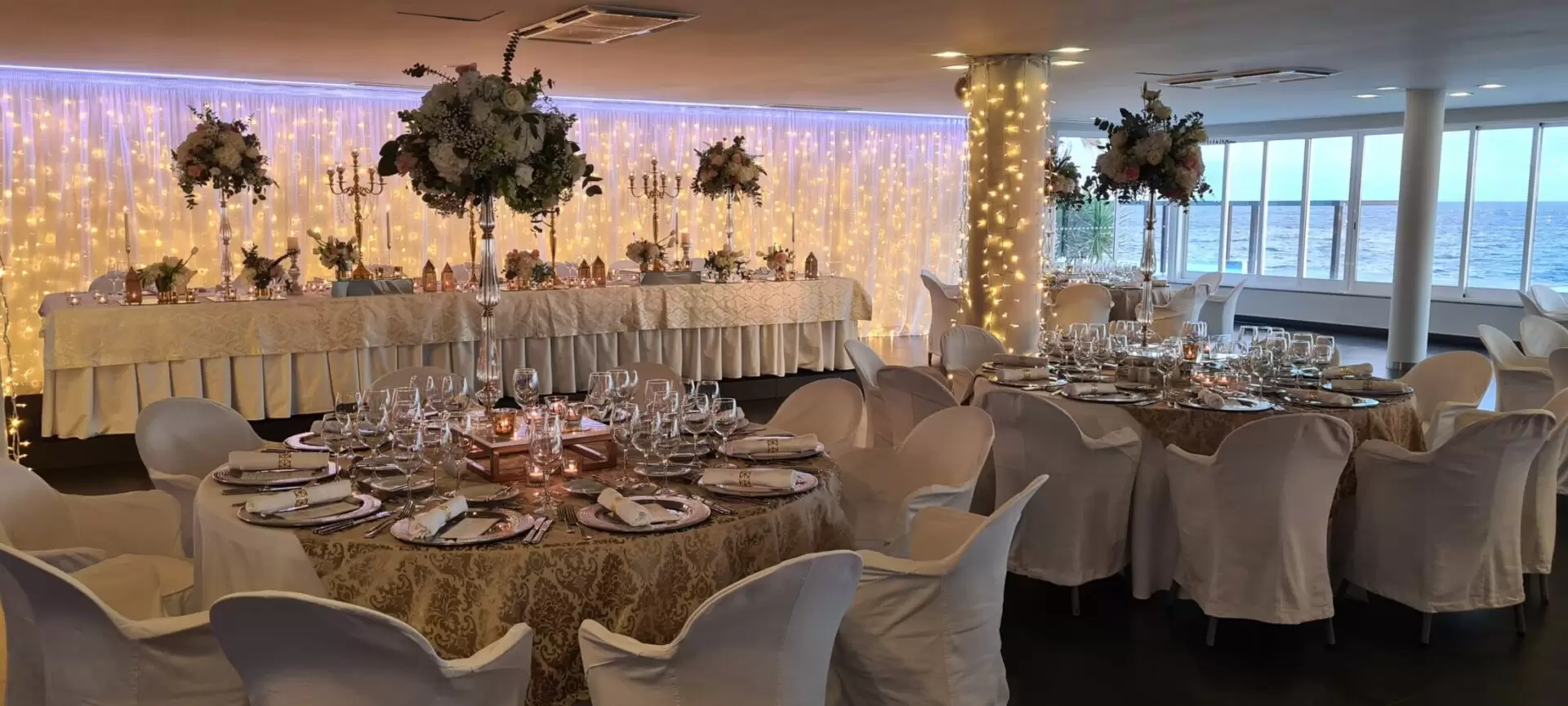 Elegant wedding reception with decorated tables and ocean view.