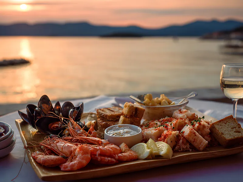 Seafood platter and wine by the sea at sunset.