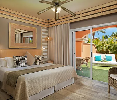 Modern hotel room with bed, ceiling fan, and sliding doors to a patio.