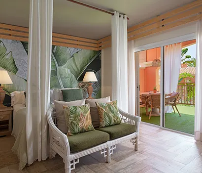 Tropical-themed room with a couch, leafy pillows, and balcony view.