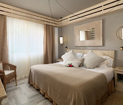 Cozy hotel room with a double bed, warm lighting, and a large window.