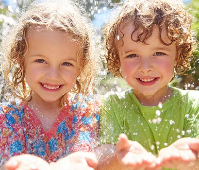Smiling children playing with water outdoors.