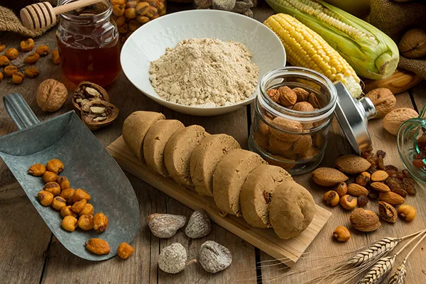 Various nuts, honey, corn, and cookies arranged on a wooden table.