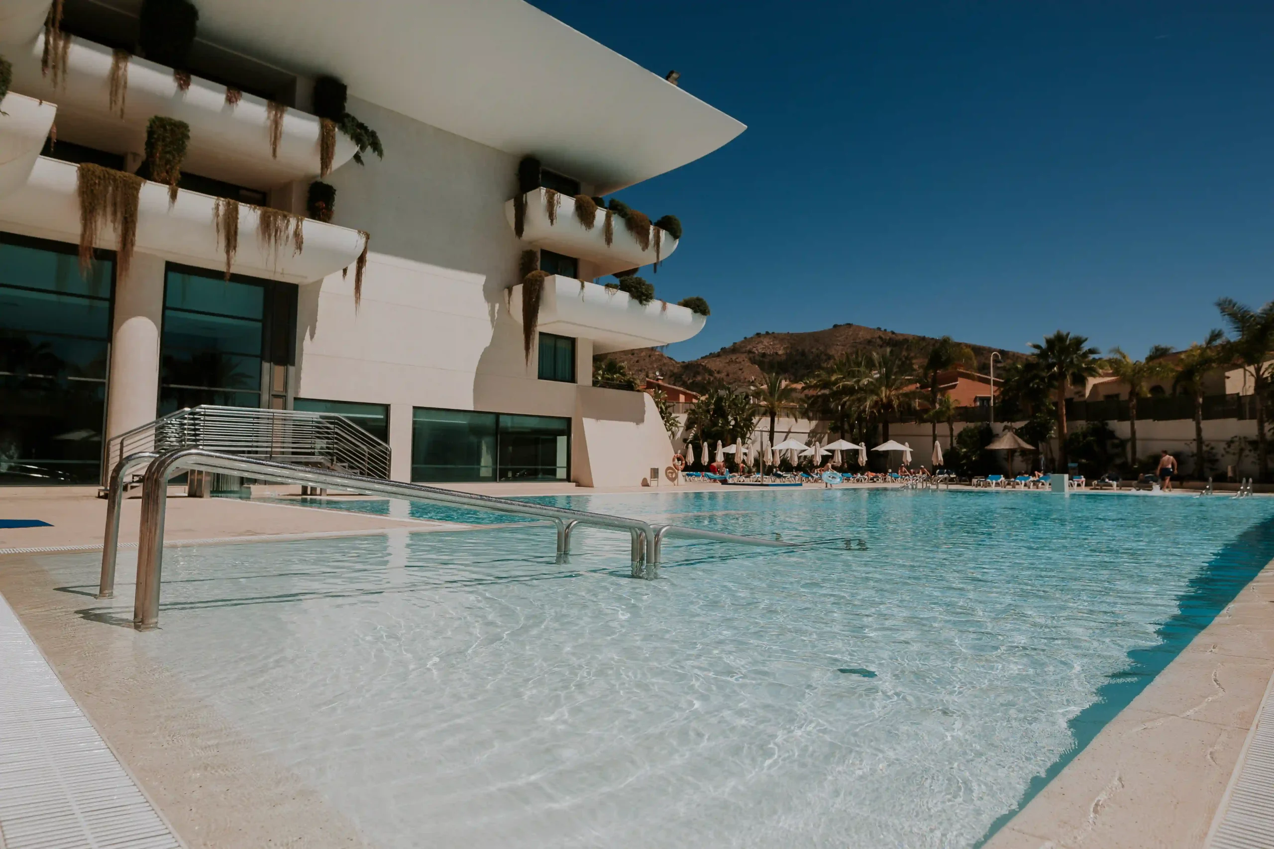 Piscina amplia junto a moderno edificio con cielo despejado.