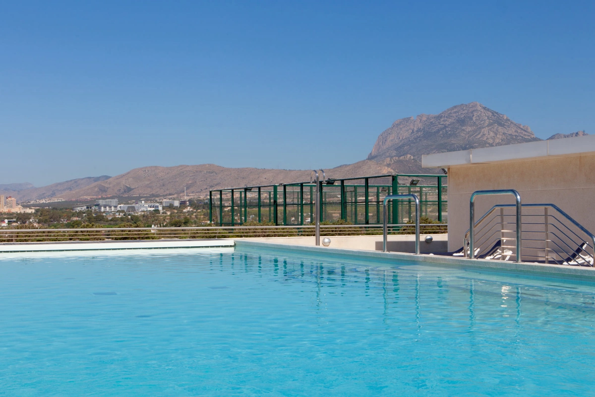 Piscina en la azotea con monta&ntilde;as al fondo bajo un cielo despejado.