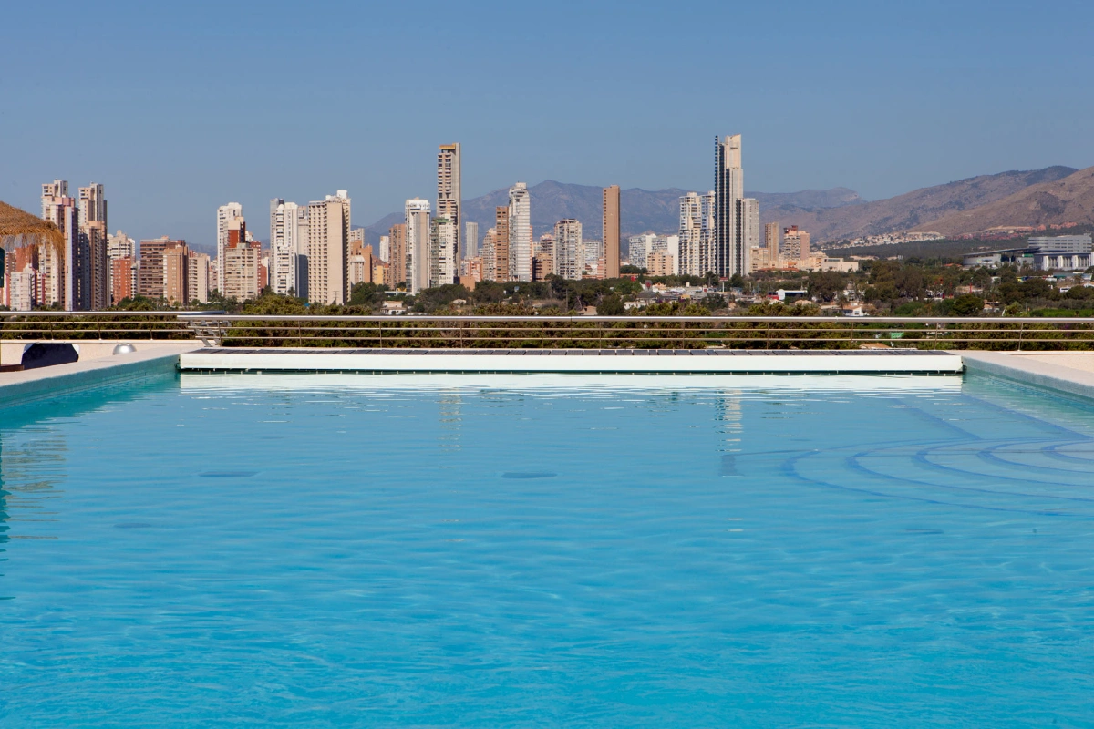 Piscina en azotea con vista a la ciudad y monta&ntilde;as al fondo.