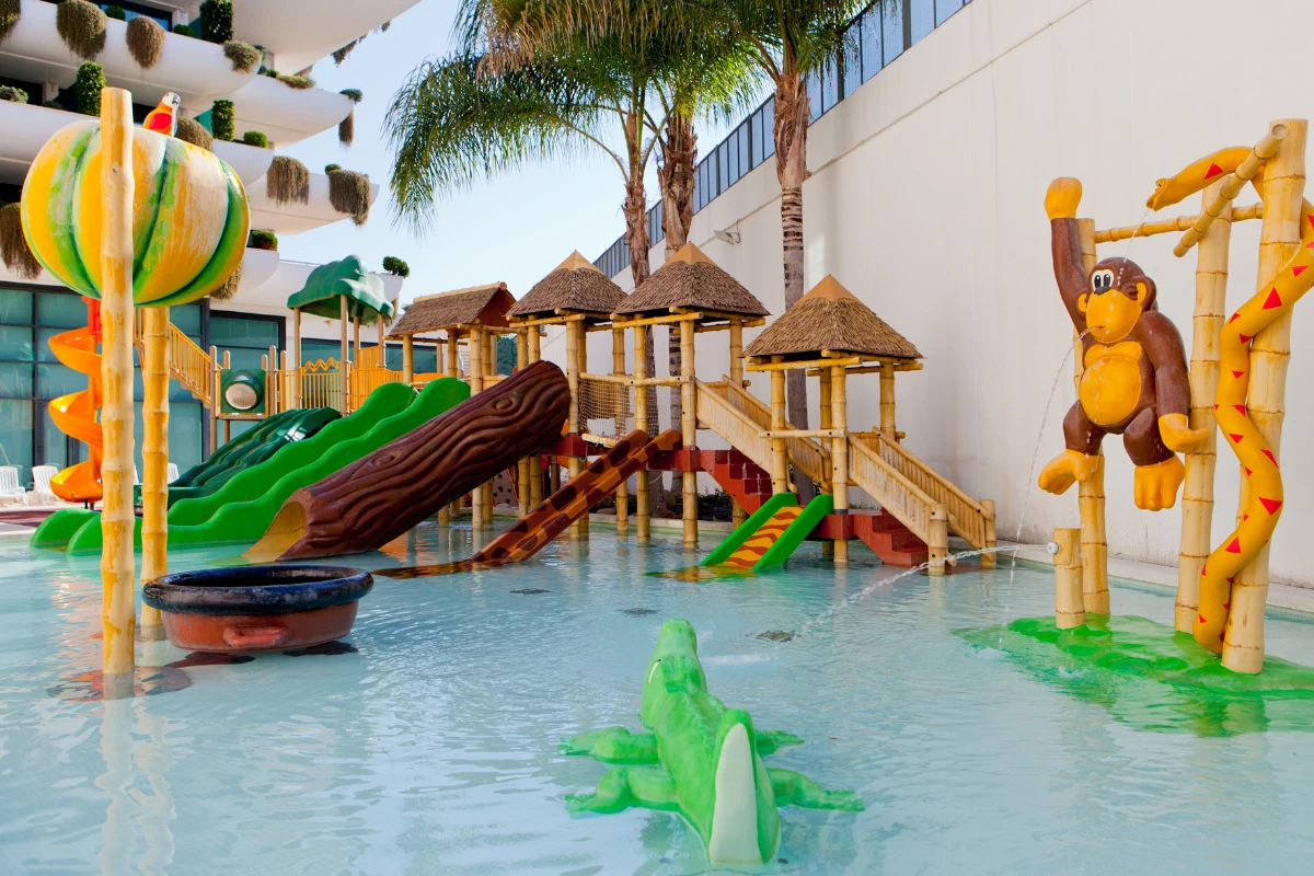 Parque acu&aacute;tico infantil con toboganes y figuras de animales en una piscina poco profunda.