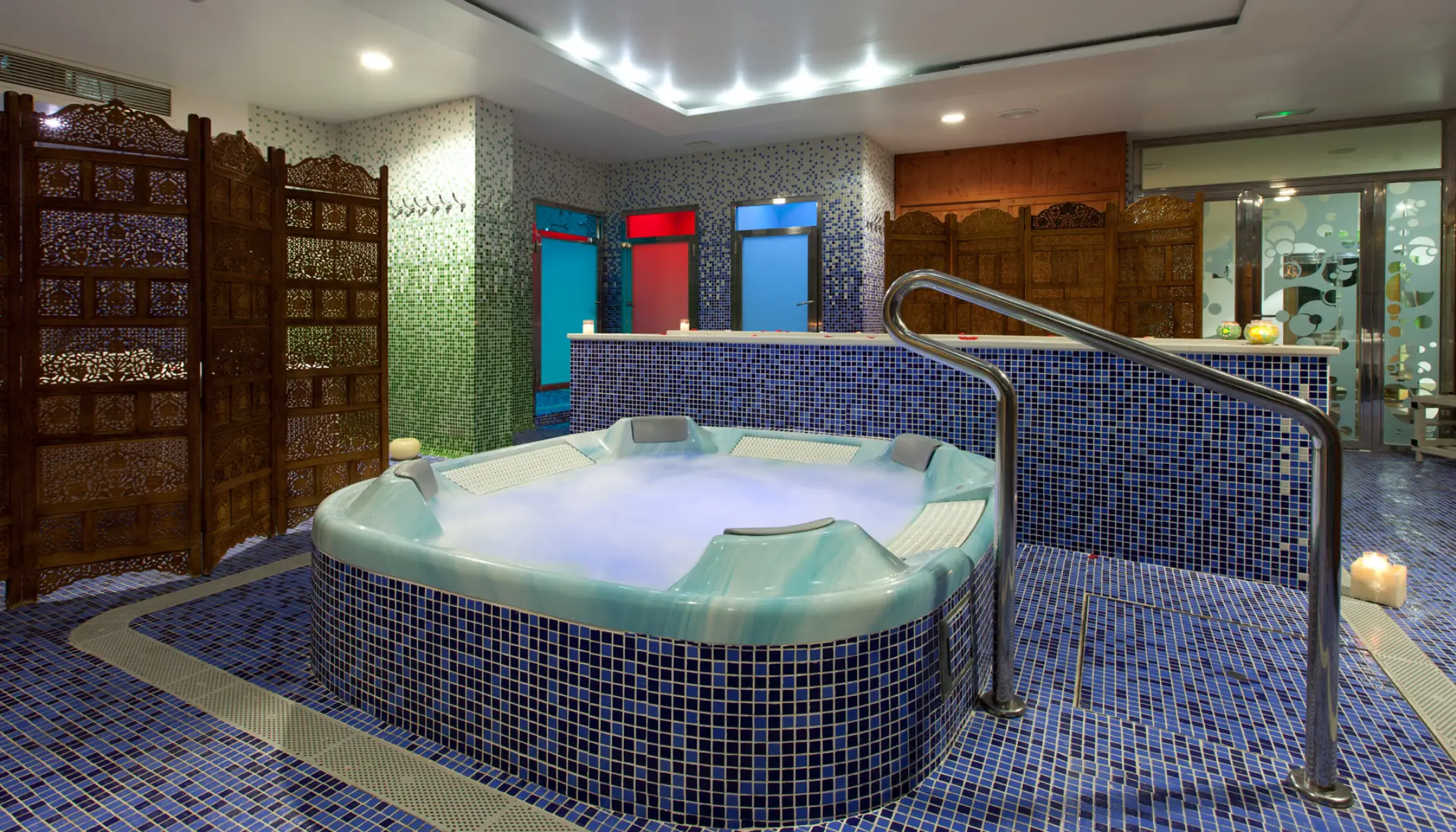 Jacuzzi rodeado de mosaicos azules y paneles decorativos de madera.
