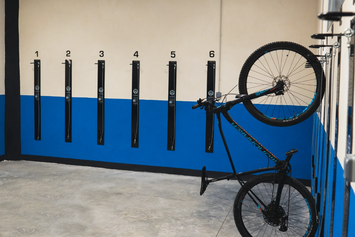 Bicicleta colgada en un soporte numerado junto a una pared azul y blanca.
