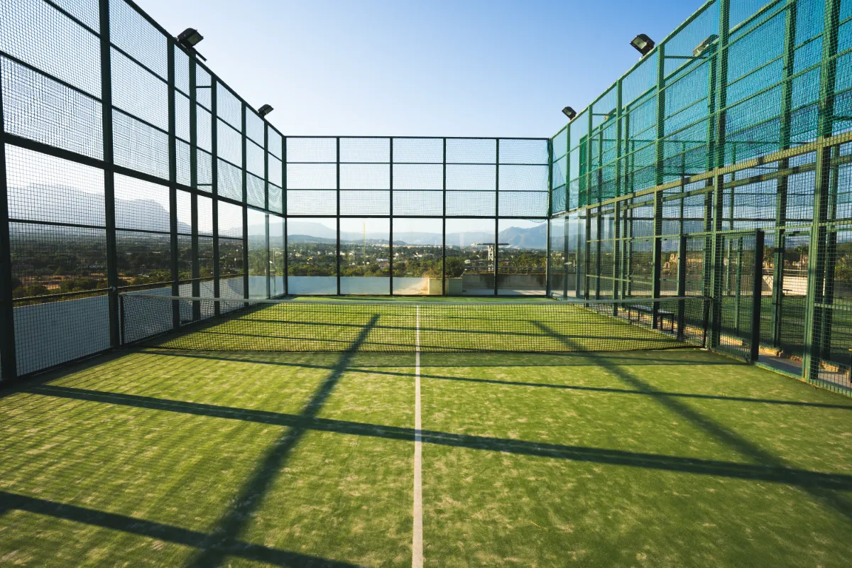 Cancha de p&aacute;del con vista a monta&ntilde;as bajo un cielo despejado.