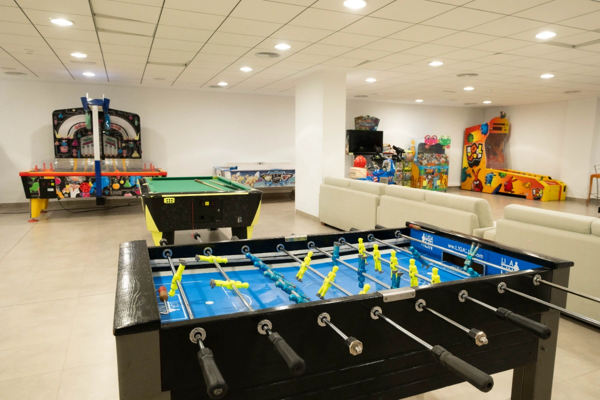 Sala de juegos con futbol&iacute;n, billar y m&aacute;quinas arcade.